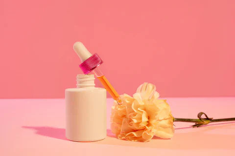 Cliganic dropper bottle of lip oil displayed against a pink background with a yellow flower, representing natural lip care and botanical ingredients.