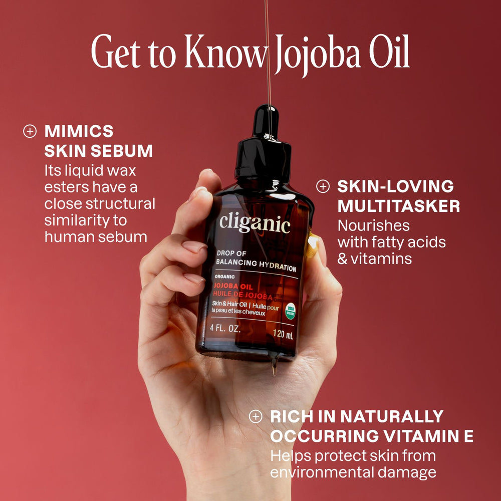 Hand holding a bottle of cliganic jojoba oil with text about jojoba oil on a red background