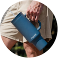 Close-up of blue tumbler cup being held outdoors, emphasizing portability and grip.